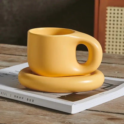 A smooth matte yellow ink splash ceramic mug with rounded handle and matching oval plate from decorbites ink splash set
