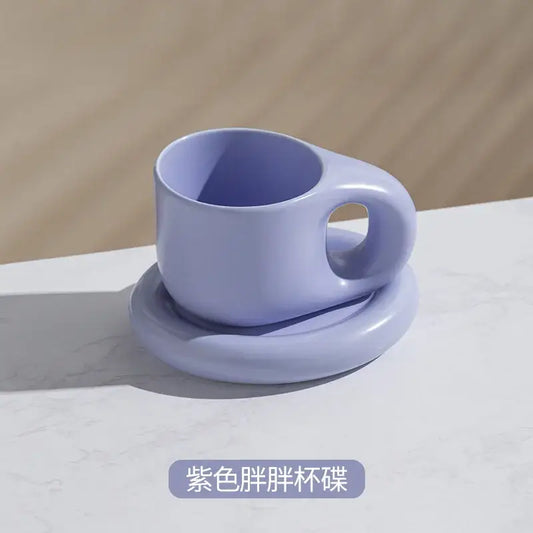 A soft lavender ink splash ceramic mug with a rounded handle on a matching oval plate from decorbites ink splash set