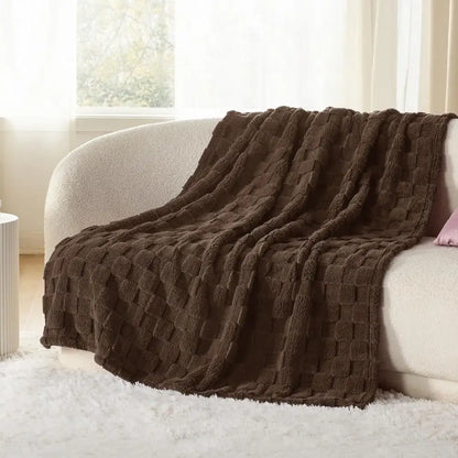 A plush chocolate-brown decorbites cozy fluffy throw blanket with textured woven pattern draped over a sofa
