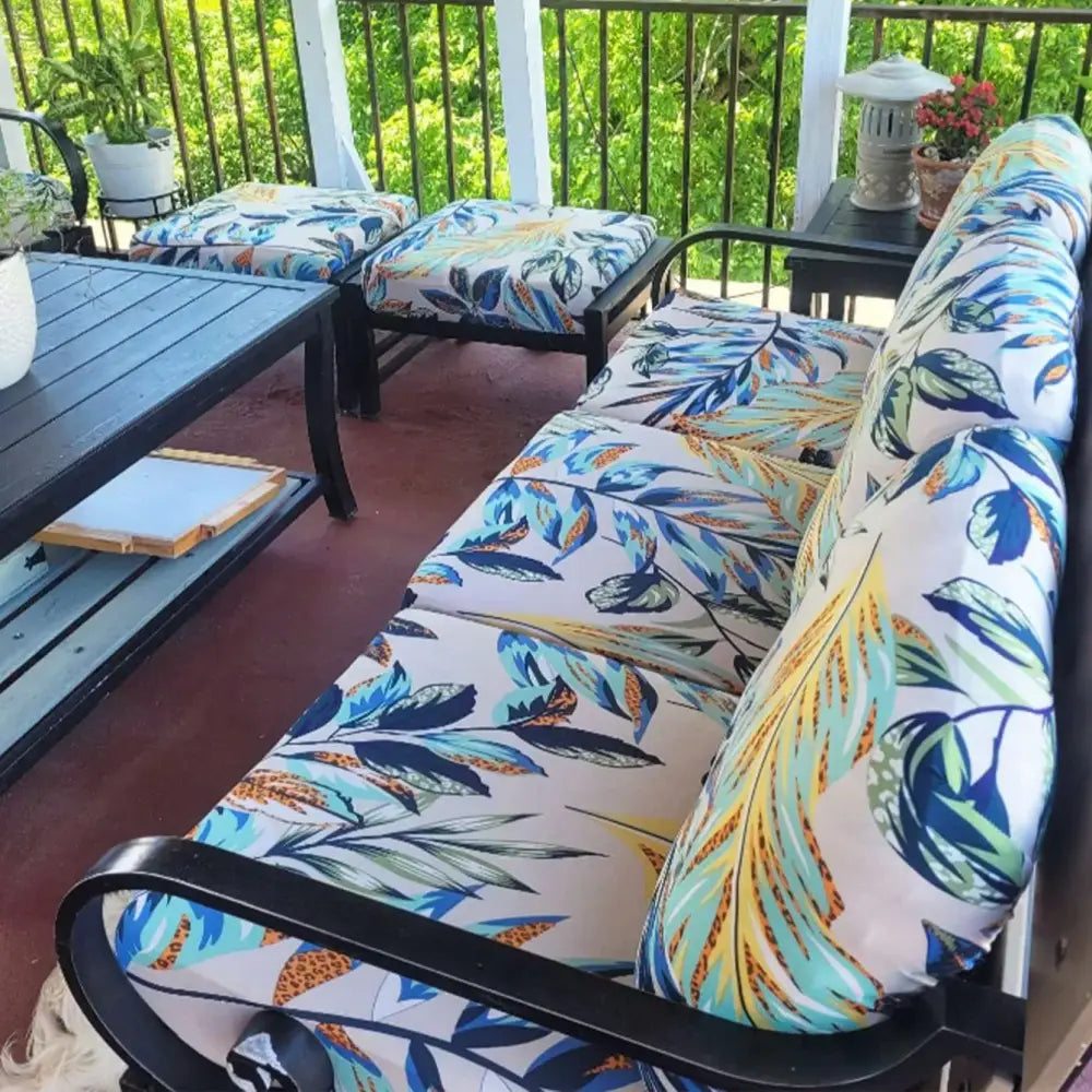 Outdoor sofa with black metal frame and vibrant leaf pattern brushed knit cushions in blue green yellow and white for patio decor