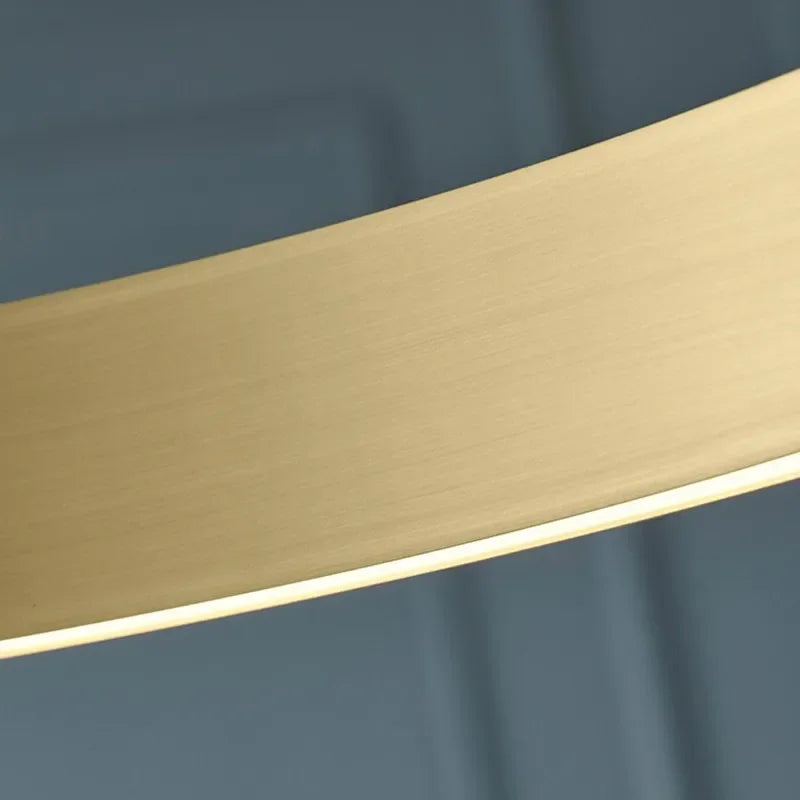 A sleek curved gold-toned metal lampshade with brushed finish in a modern led chandelier light fixture