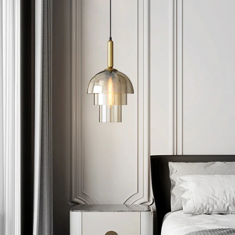A modern LED vintage art champagne chandelier glass pendant lamp with tiered smoked glass and brass accents above a bedside table