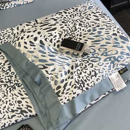 A luxurious cream satin leopard print pillow sham with bold black and blue pattern and light gray piping decorbites leopard print