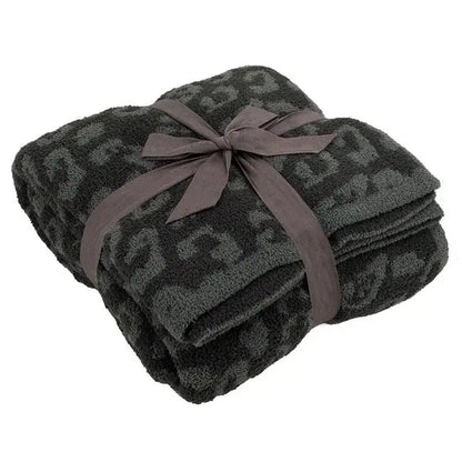 A plush dark gray leopard print fleece blanket tied with a matching satin ribbon by decorbites for sofa or bedroom
