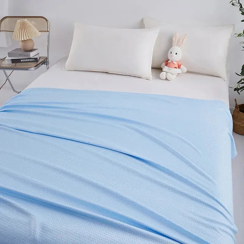 Light blue bamboo fiber summer quilt with diamond grid texture draped over a bed for decorbites bamboo fiber use