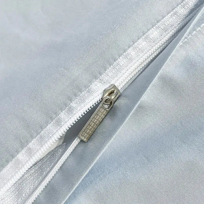 Silver-toned zipper with textured pull tab on light blue egyptian cotton embroidery duvet cover bedding set against gray fabric