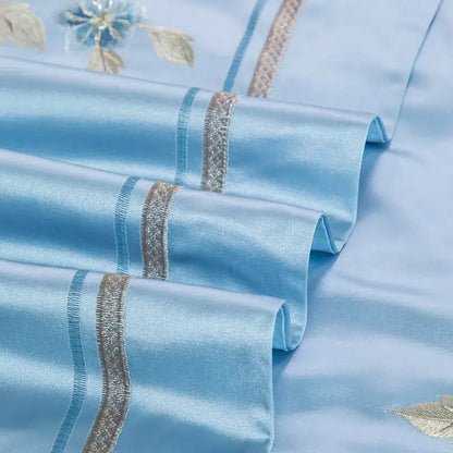 Light blue satin pillowcases with delicate floral embroidery and silver stripes in a 200s cotton embroidery bedding set
