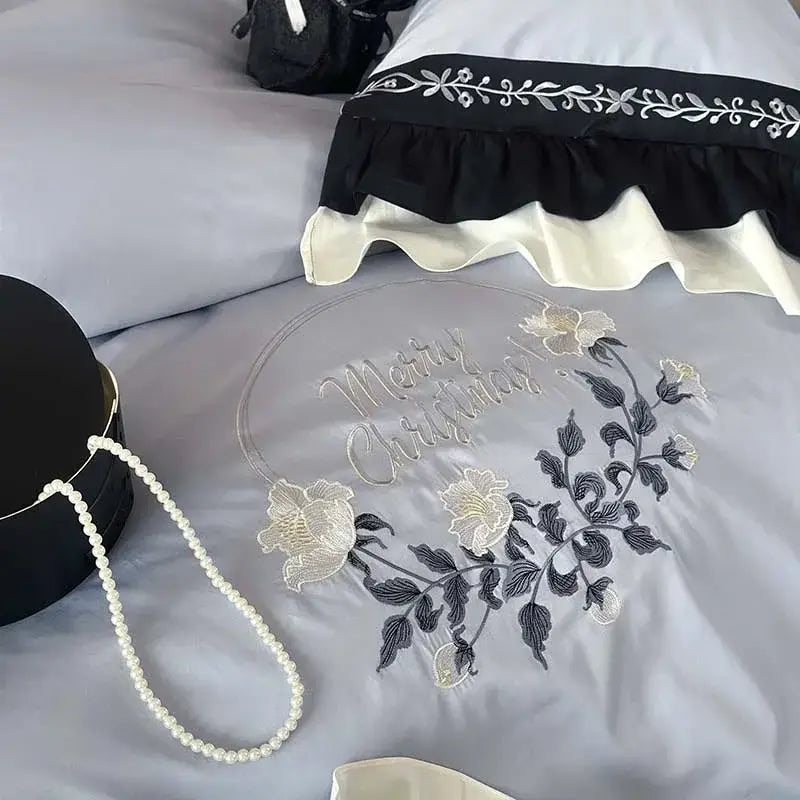 A delicate silver merry christmas wreath with embroidered white and black flowers rests on light gray satin bedding set decorbites flowers embroidery