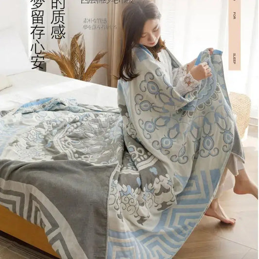 A light blue and gray patterned cotton gauze summer blanket draped over a woman’s shoulders by decorbites cotton gauze