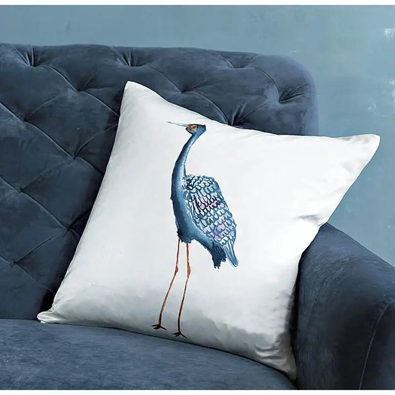 White cushion with blue crane detailed embroidery featuring iridescent feathers and orange legs silk throw pillow cover