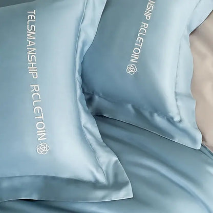 Light blue satin cotton embroidery pillowcases with white embroidered text and logo in a decorbites bedding set