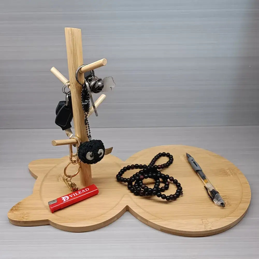 Light brown cat wooden key rack holder with bear-shaped base holding keys black necklace and red lighter