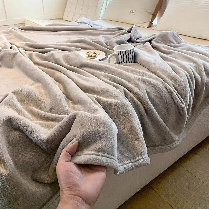 A light gray coral velvet summer blanket with a soft plush textured surface and neatly finished edges by decorbites