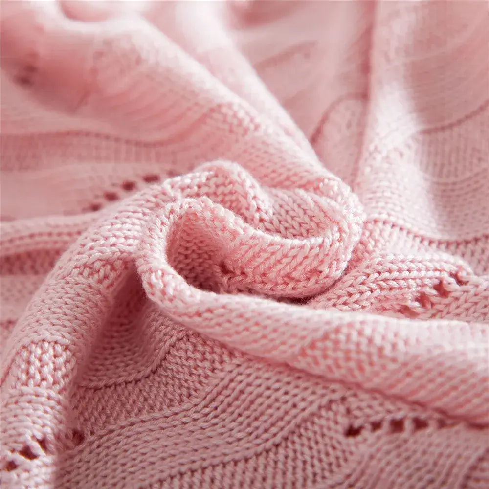 A soft pink knitted sweater with cable knit and lace detailing paired with a light green decorbites bamboo knitted cooling blanket