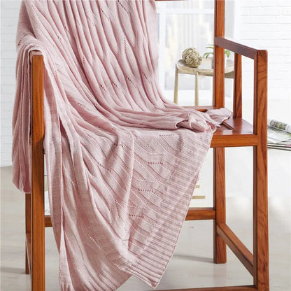 A soft pink bamboo knitted cooling blanket with a ribbed pattern draped over a wooden chair decorbites cooling blanket