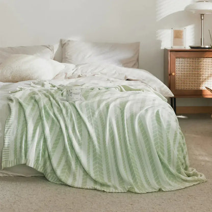 A soft mint green bamboo knitted cooling blanket with a subtle leaf pattern draped over a bed decorbites cooling blanket