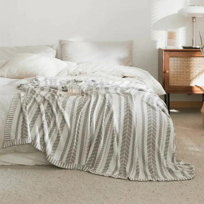 A soft off-white bamboo knitted cooling blanket with subtle gray geometric pattern draped as a bedroom throw