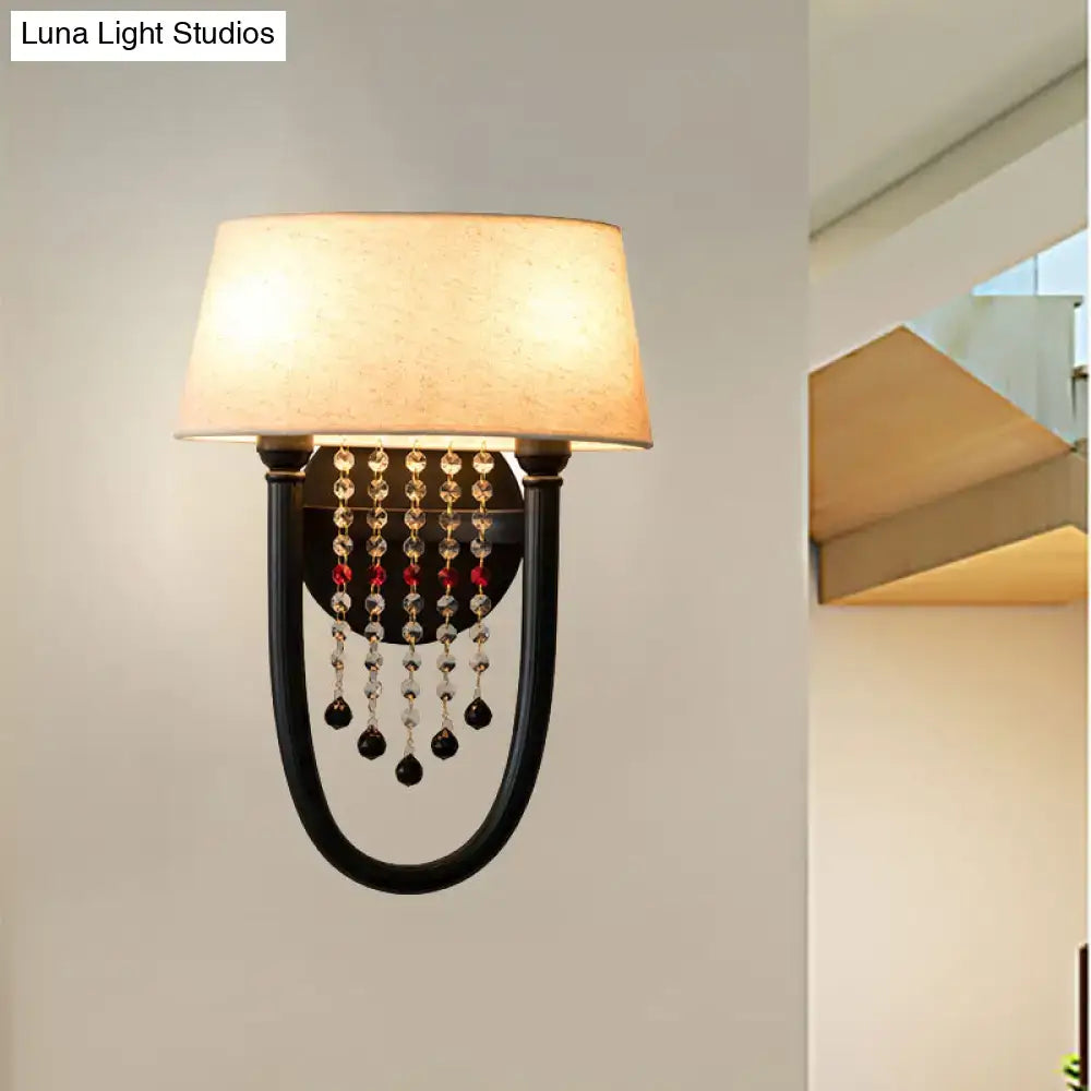 Black wrought iron wall lamp with beige fabric drum shade and cascading clear red and dark crystal bead detail