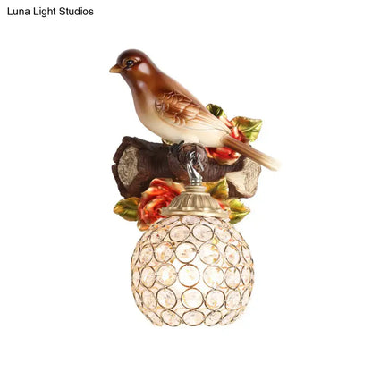 Lodge brown and cream bird wall sconce with ornate base and crystal global shade featuring red roses and branch design