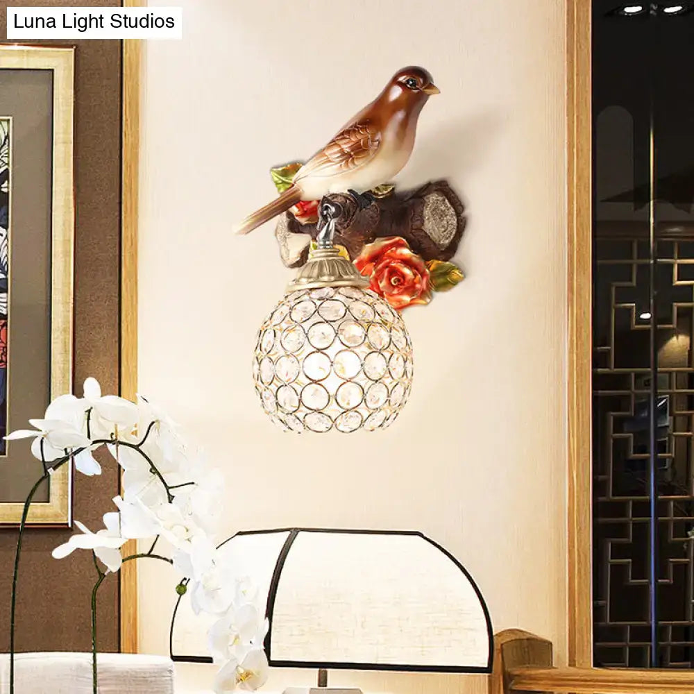 Lodge brown and cream bird wall sconce with crystal global shade featuring a detailed bird and floral accents