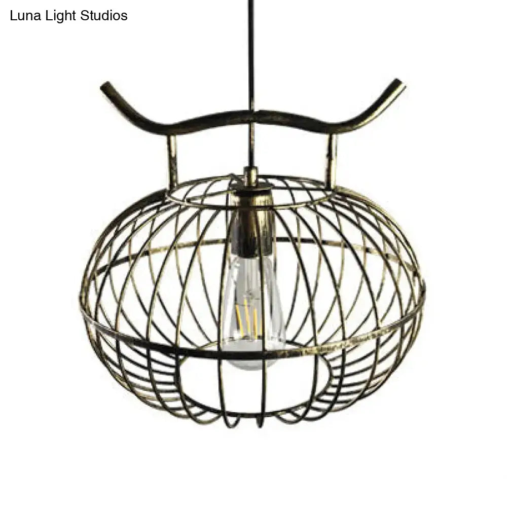 Antique brass cage-style pendant light with visible edison bulb in rust aged brass finish with lantern design