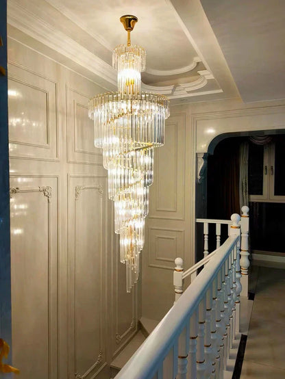 A long crystal staircase gold chandelier with cascading clear glass rods and a gold finish, ideal for a hotel hall