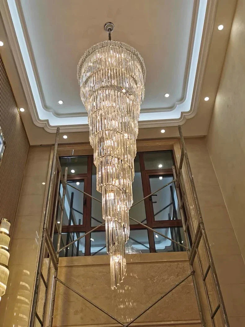 A cascading crystal staircase gold chandelier with tiered faceted glass elements for hotel hall or luxury villa decor