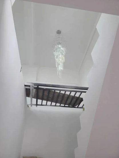 A long crystal staircase gold chandelier with cascading clear glass prisms for hotel hall and luxury home decor
