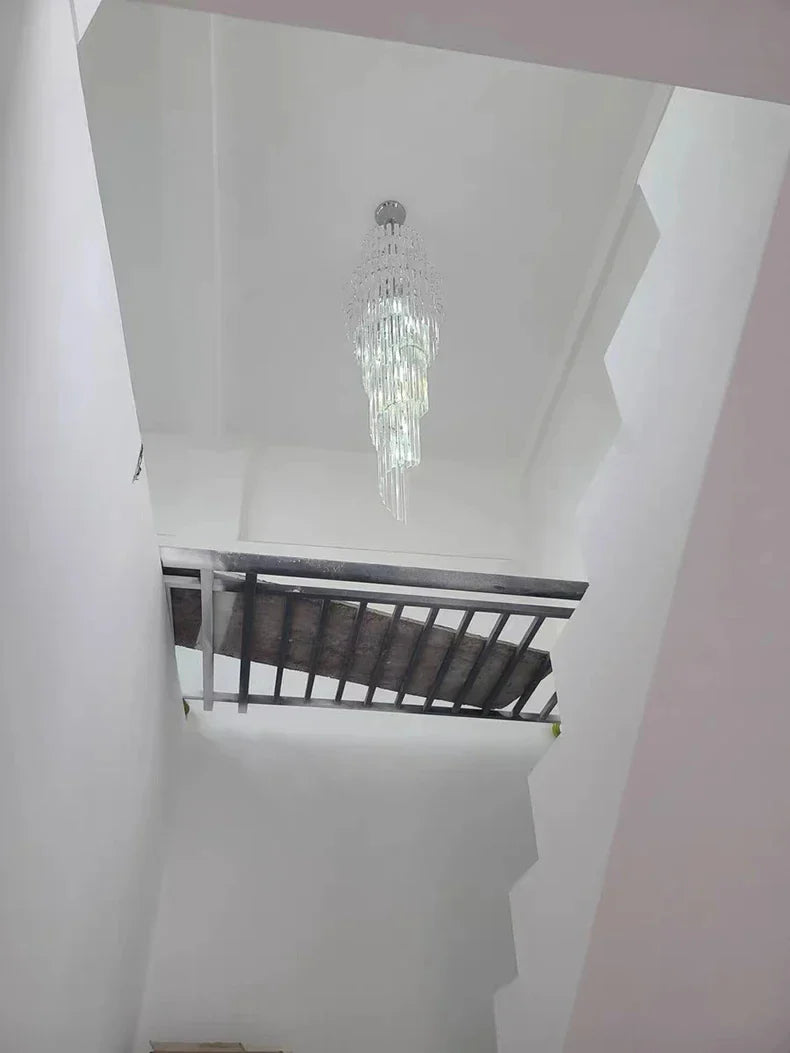 A long crystal staircase gold chandelier with cascading clear glass prisms for hotel hall and luxury home decor