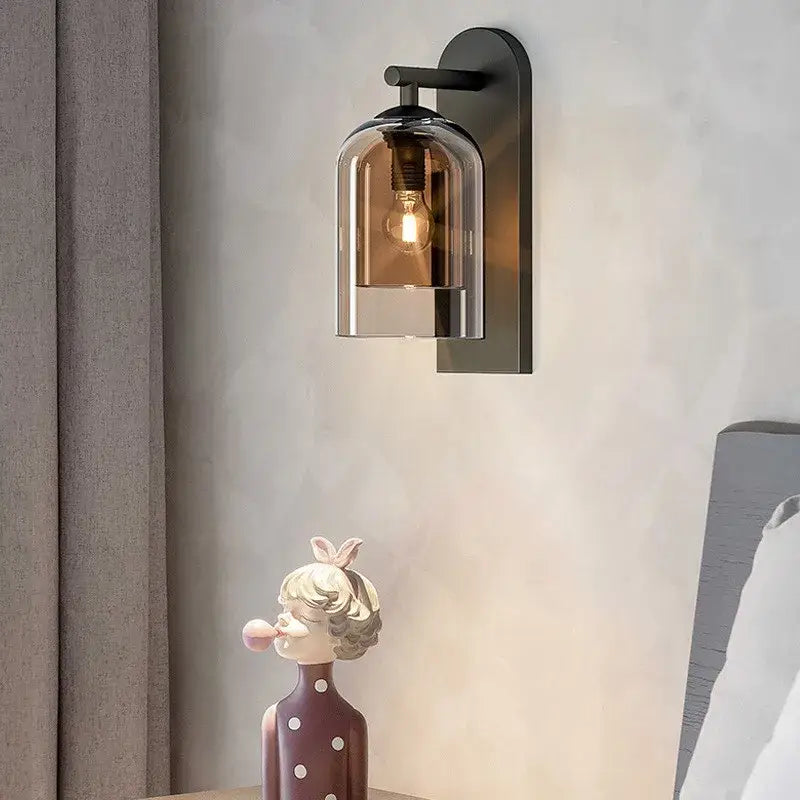 Black metal wall art light with clear bell-shaped amber glass shade housing exposed filament bulb for bedroom use