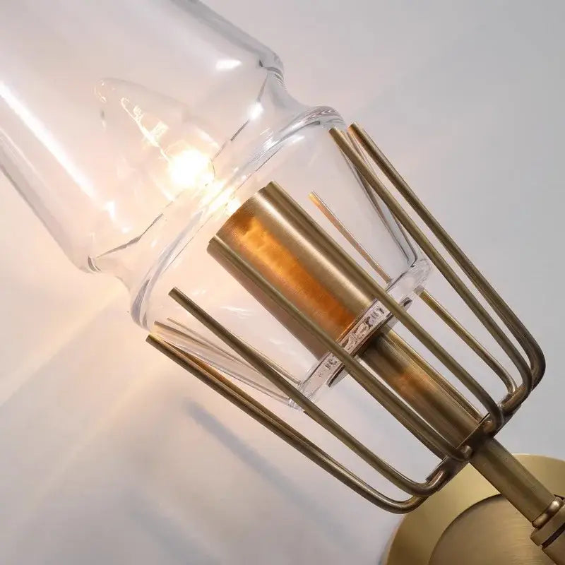 A brass-finished industrial wall sconce with clear glass shade and cage, ideal as a decorbites copper lighting fixture