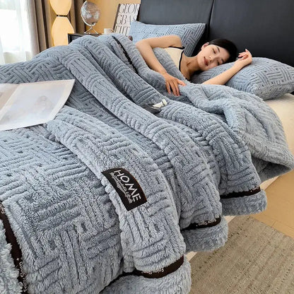 A cozy light blue luxury coral fleece blanket with textured woven pattern and black trim for winter bedroom use