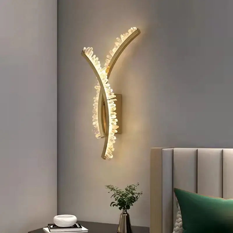 Luxury crystal gold metal wall sconce with y-shaped gold metal design and faceted decorbites crystal gold elements emitting warm glow