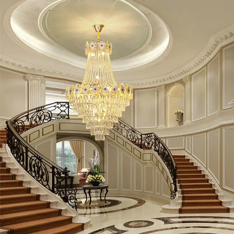 A multi-tiered decorbites gold round chandelier with blue crystal stair lights and gold accents hangs from a ceiling medallion