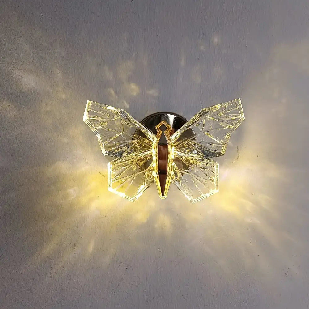 Luxury gold butterfly wall lamp featuring a clear crystal geometric butterfly with a metallic mounting base for bedroom lighting