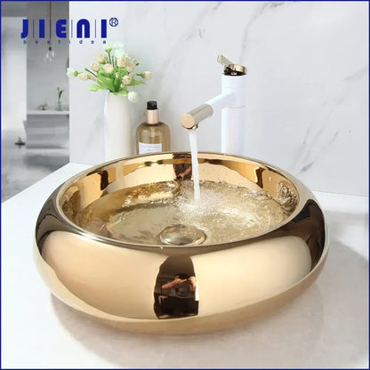 Gold-colored glossy ceramic vessel sink with modern design paired with luxury bath mixer set for bathroom use