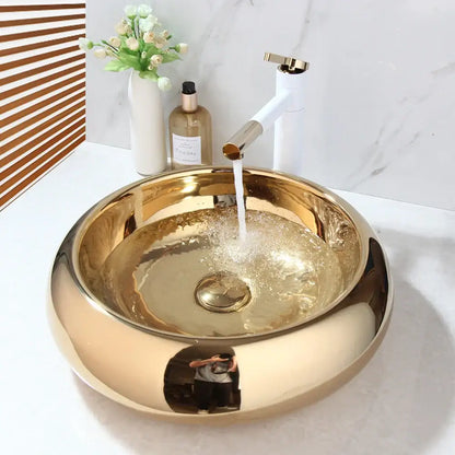 Luxury gold ceramic vessel sink with round reflective finish paired with a matching bath mixer set for bathrooms