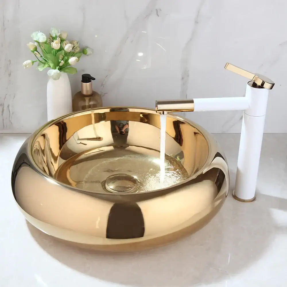 Luxury gold ceramic vessel sink with a shiny gold finish and sleek white bath mixer set featuring gold accents
