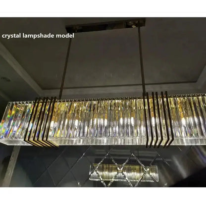 A modern luxury gold crystal rectangular pendant light with clear faceted prisms for dining room decorbites gold lustre