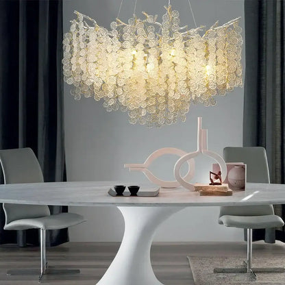A luxury gold money tree crystal chandelier with intricate leaf metalwork hangs above a modern dining table