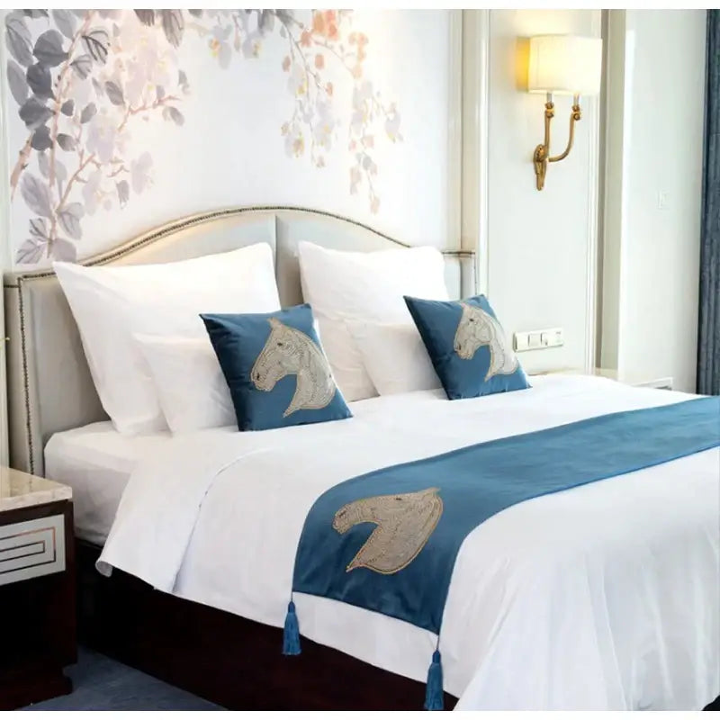 Blue satin bed runner with embroidered horse heads and tassels paired with decorbites gold rhinestone square pillow