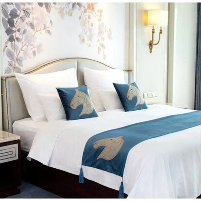 Blue satin bed runner with embroidered horse heads and tassels paired with decorbites gold rhinestone square pillow