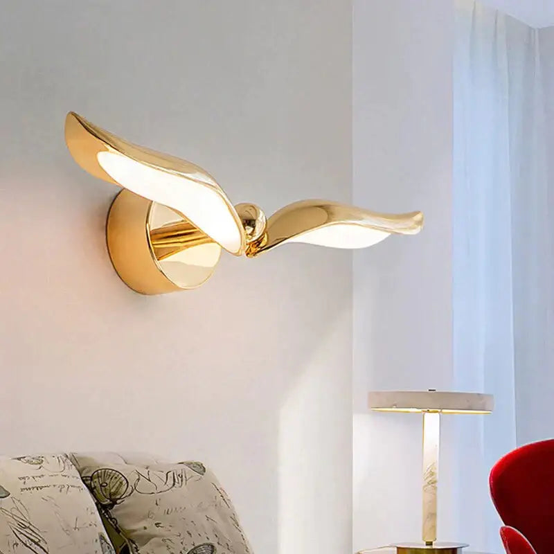 Gold-colored luxury minimalist creative seagull wall lamp with sleek reflective metal wings for bedroom and living room