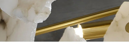 Gold-toned cylindrical rods resting against white marble crystalline rock in a marble led chandelier round pendant light
