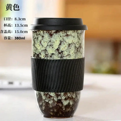 A yellow decorbites ceramic kiln mug with intricate crackled glaze and black silicone grip for travel or kitchen use