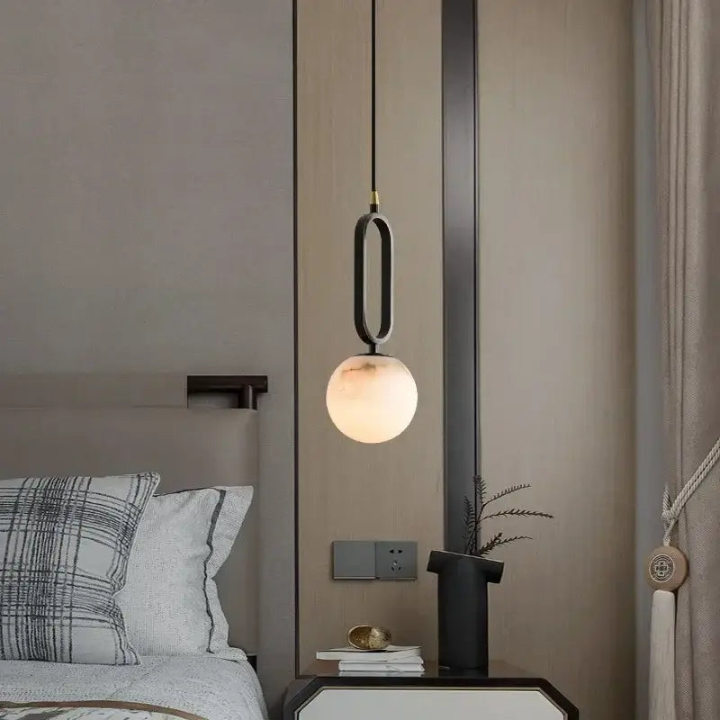 Matte black pendant light with polished copper accents and frosted glass globe ideal for dining room use