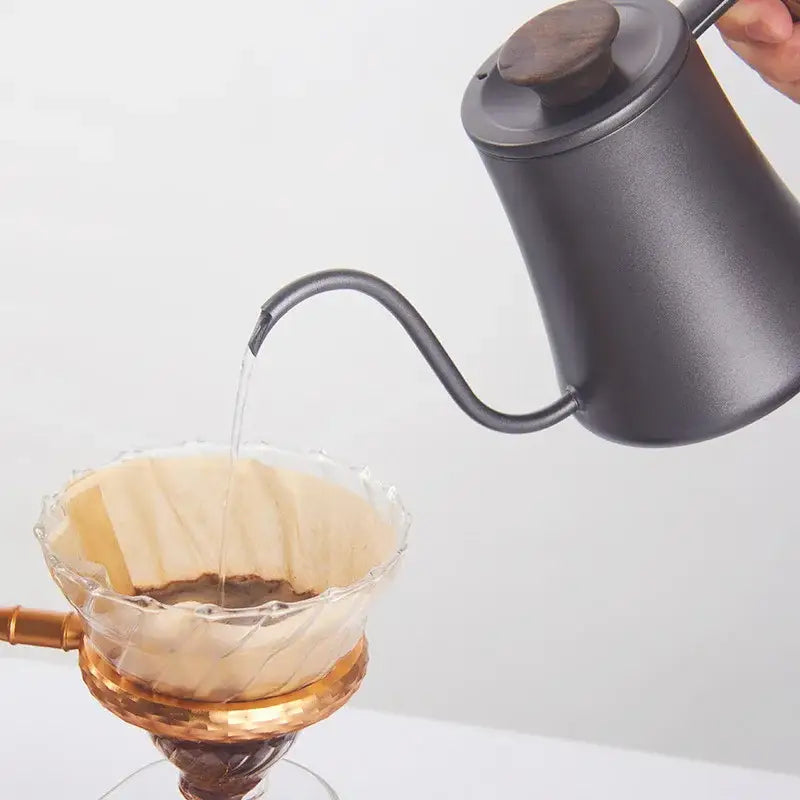 Matte black gooseneck pour over kettle with wood handle by decorbites pouring water into glass coffee dripper