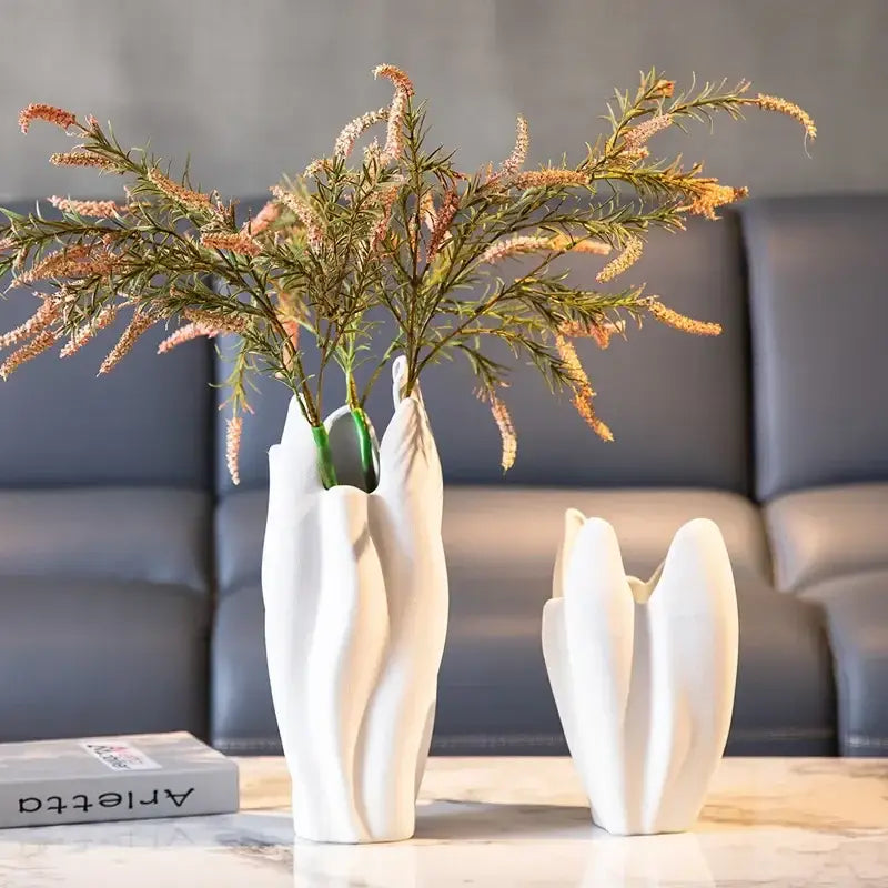 White ceramic irregular pleated ceramic vase with leaf design holding artificial pink and green flowers for living room decorbites decor