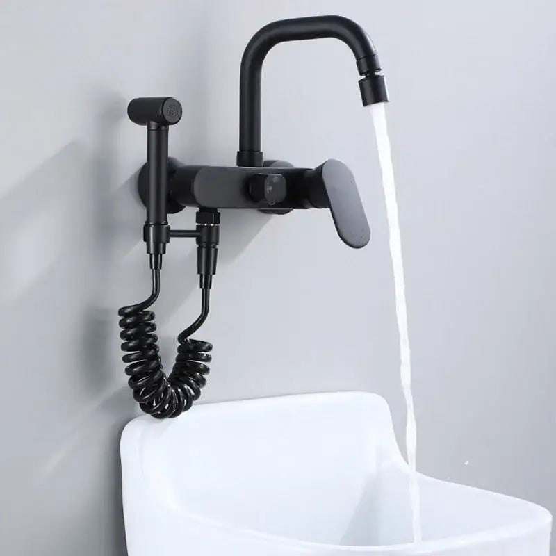 Matte black kitchen mixer tap with curved spout and integrated handheld showerhead on coiled hose wall mounted