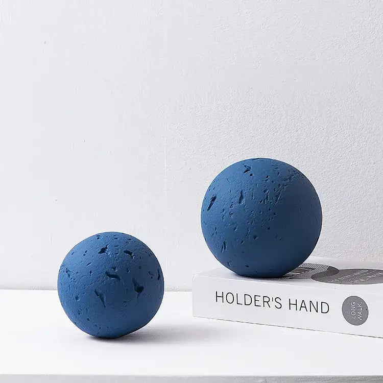Two matte blue geometric spherical home decoration accessories with a textured porous volcanic rock surface for living room decor